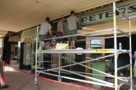 Three Harradence employees erecting the sign in front of the cafe (eastern face) 